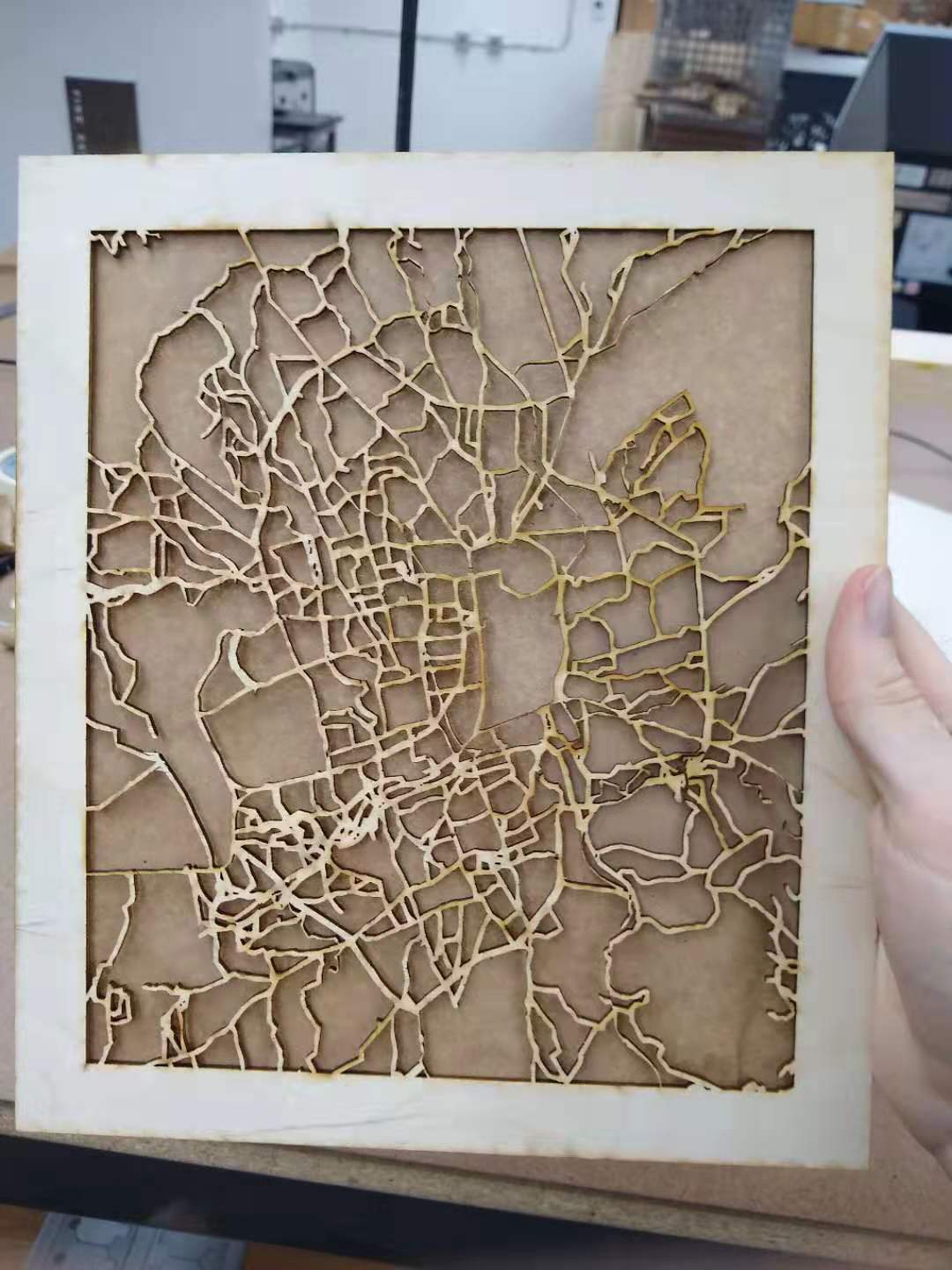 A laser-cut city map with paper taped to the back.